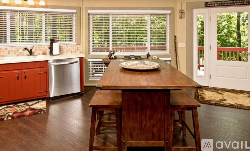A kitchen with a wooden table and chairs in front of a window with blinds.
