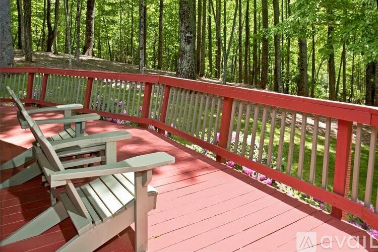 A red wooden deck with two chairs and a table.