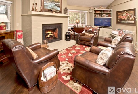 A living room with brown leather chairs and a fireplace.