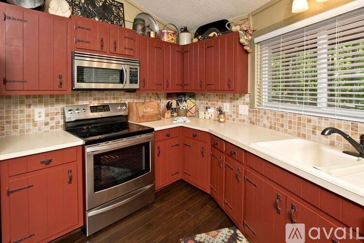 A kitchen with red cabinets and a stainless steel oven.