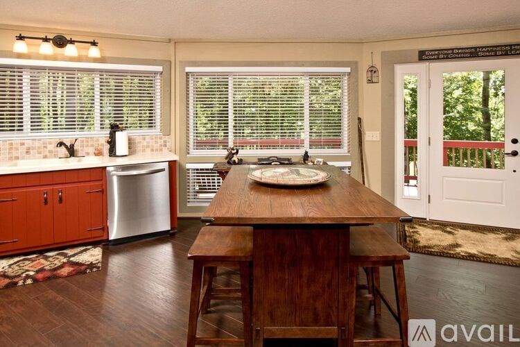 A kitchen with a wooden table and chairs in front of a window with blinds.