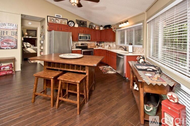 A kitchen with wooden floors and a table with two stools.