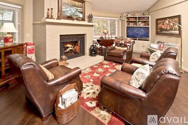 A living room with brown leather chairs and a fireplace.