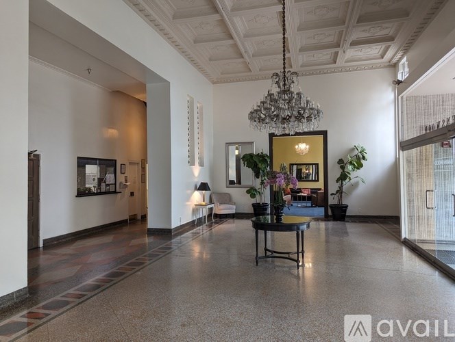 A spacious room with a chandelier and a table with a vase of flowers on it.