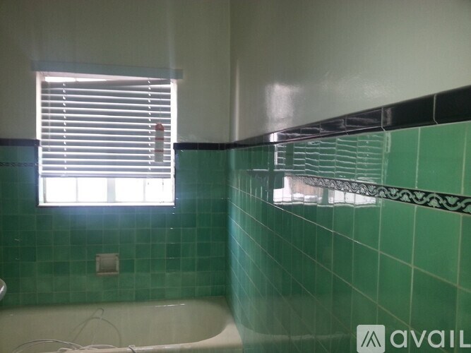 A bathroom with green tiles and a white tub.