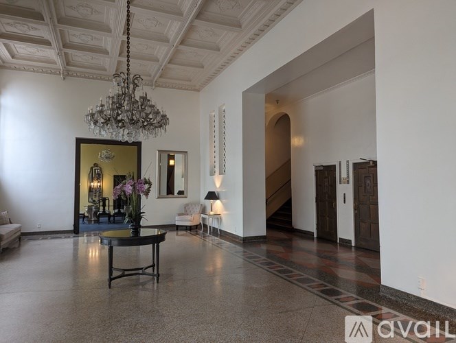 A spacious hallway with a chandelier, a coffee table, and a staircase.