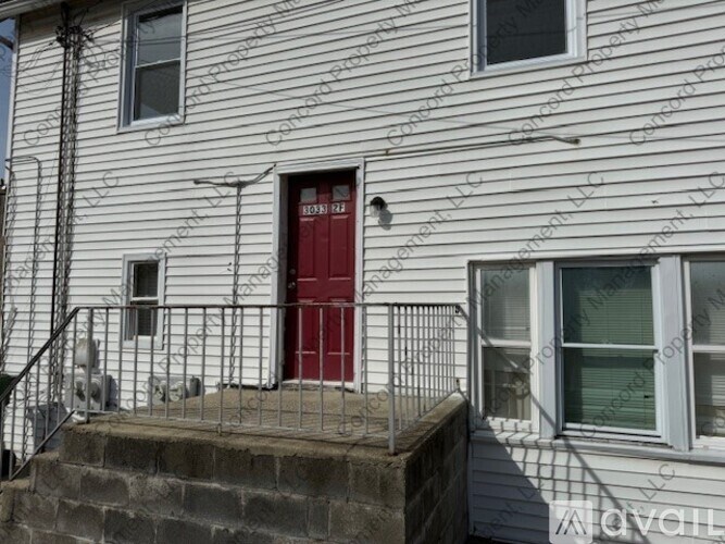 A white house with a red door and a metal railing.