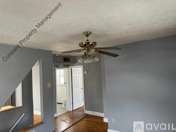 A room with a ceiling fan and a door leading to a bathroom.