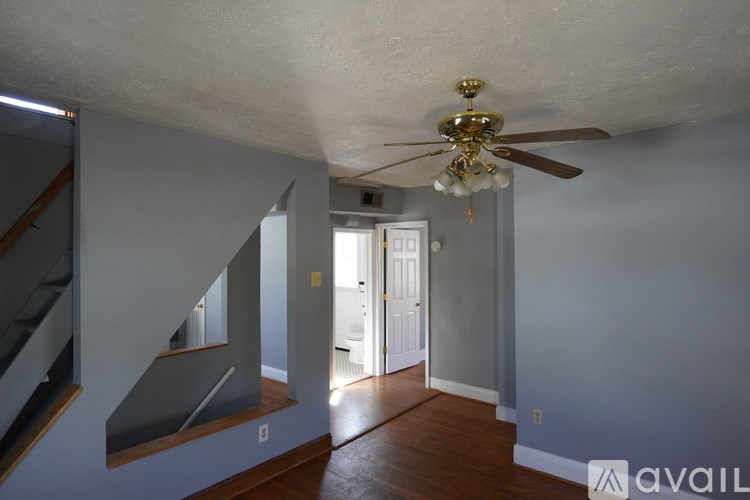 A room with a ceiling fan and a staircase.