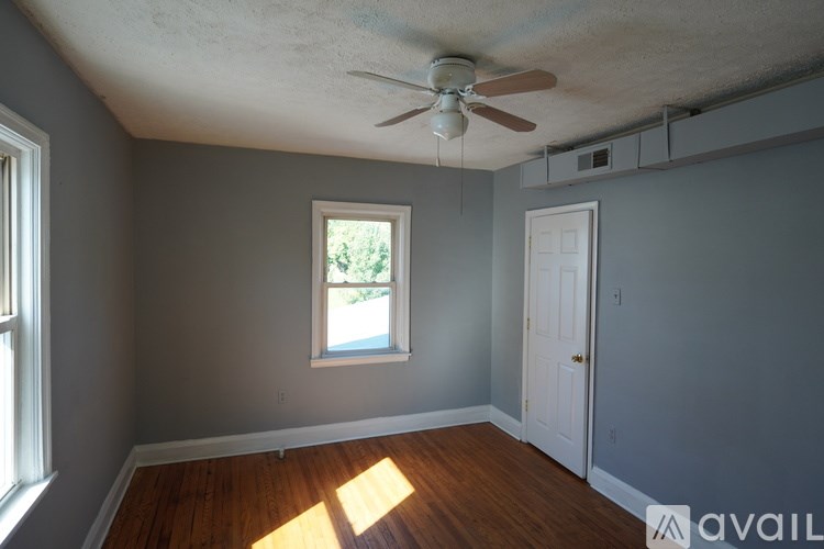 A room with a ceiling fan and a window letting in sunlight.
