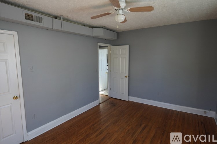 A room with a ceiling fan and wooden floors.