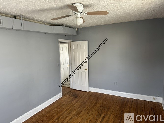 A room with a white door and a ceiling fan.