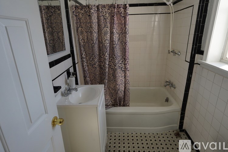 A bathroom with a white door, a sink, a bathtub, and a shower curtain.