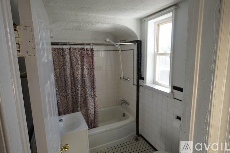 A bathroom with a bathtub, shower curtain, and a window.