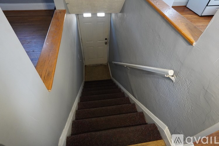 A staircase with a brown carpeted runner and a white wall.