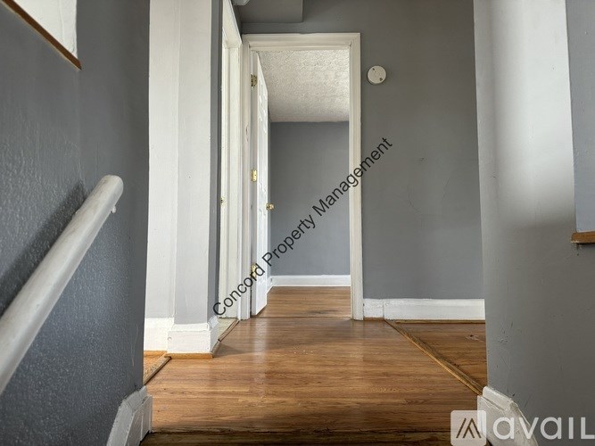 A hallway with a wooden floor and white walls.