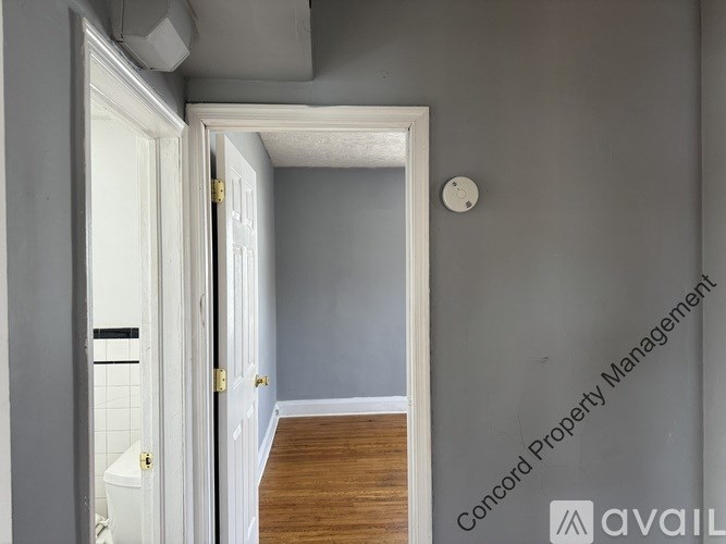 A hallway with a white door and a wooden floor.