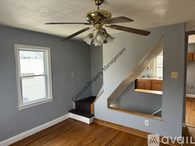 A living room with a staircase and a ceiling fan.