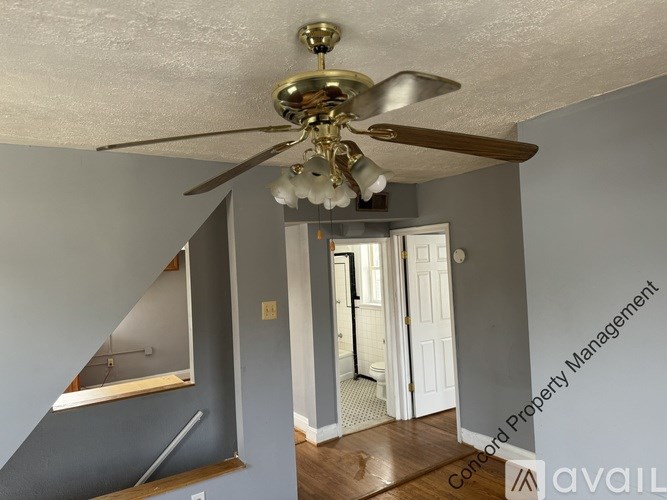 A room with a ceiling fan and a staircase.