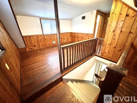 A wooden staircase with a railing leads up to a door.
