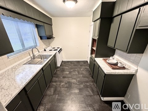 A kitchen with black cabinets and a marble countertop.
