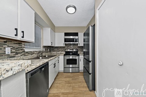 A kitchen with a marble countertop and stainless steel appliances.