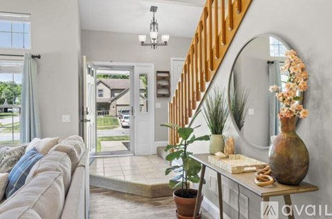 A living room with a grey sofa and a wooden staircase.