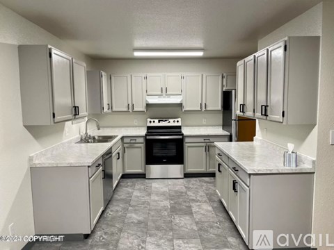 A kitchen with white cabinets and a marble countertop.