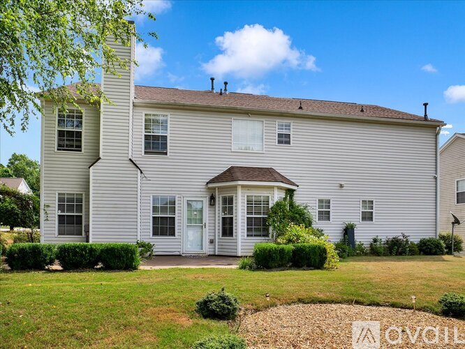 A two-story house with a front yard and a small garden.