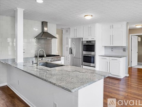 A kitchen with white cabinets and a marble countertop.