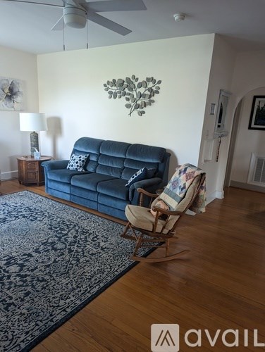 A living room with a blue couch and a rocking chair.