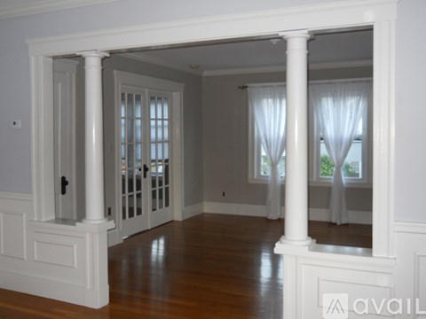 A room with white columns and wooden floors.