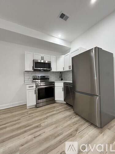 A kitchen with a stainless steel refrigerator, microwave, oven, and range hood.