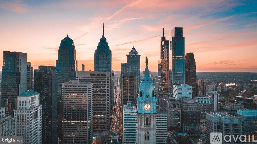 A city skyline at sunset with a mix of modern and older buildings.