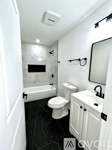A white bathroom with a black toilet and a black and white tiled floor.