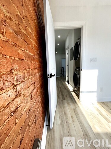 A hallway with a brick wall on the left and a white door on the right.