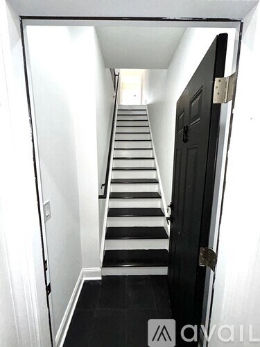 A hallway with a staircase and a black door.