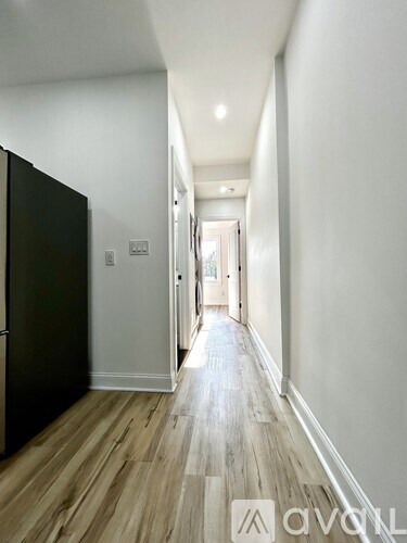 A long hallway with wood floors and white walls.