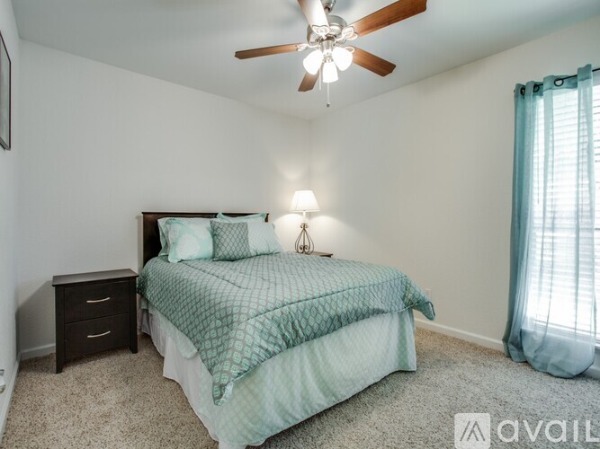 A bedroom with a bed, nightstand, and a ceiling fan.
