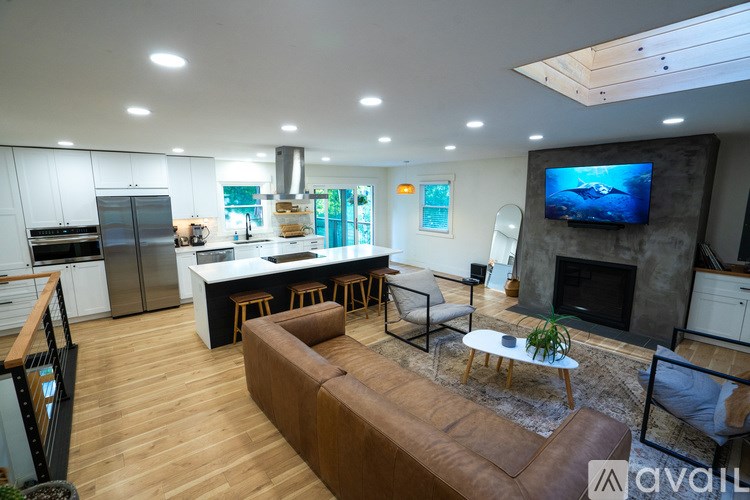 A modern kitchen with a brown leather couch and a television mounted above the fireplace.