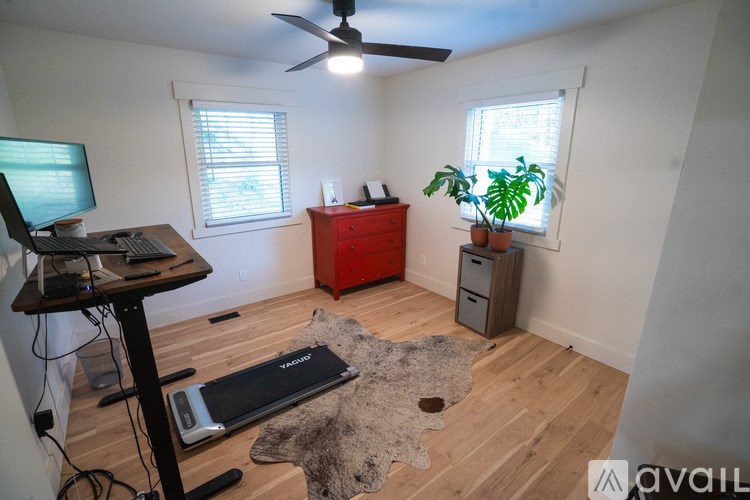 A room with a ceiling fan, a desk with a computer, and a red cabinet.