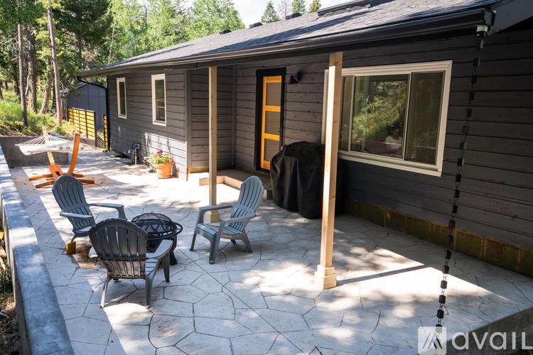 A patio with a table and chairs is in front of a house.