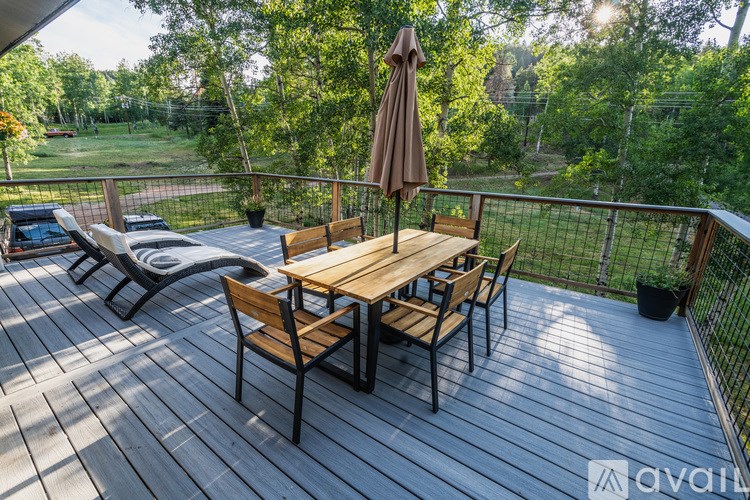 A wooden table with chairs and an umbrella on a deck.