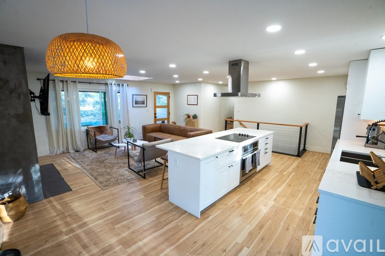 A modern kitchen with wooden floors and a white island.