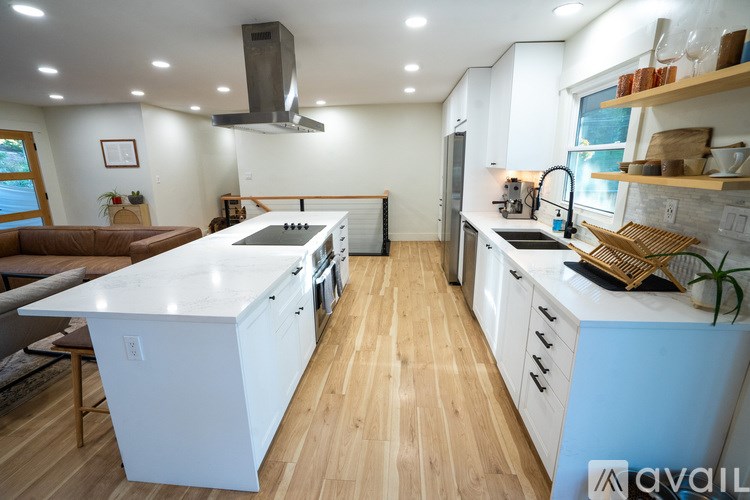 A modern kitchen with white cabinets and a wooden floor.