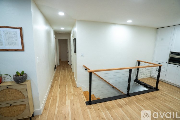 A long hallway with a wooden floor and a black railing.