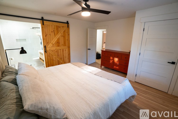 A bedroom with a bed, a ceiling fan, and a wooden door.