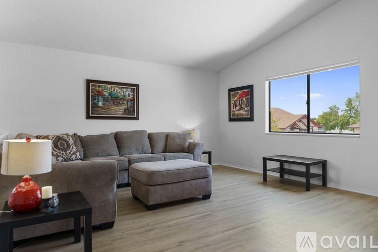 A living room with a grey couch, a red lamp, and two pictures on the wall.