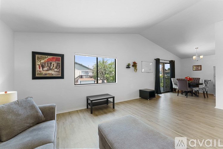 A living room with a grey couch and a painting on the wall.