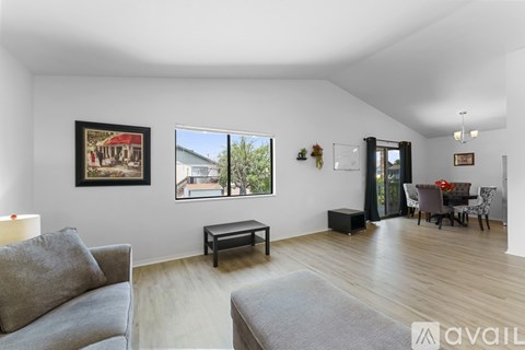 A living room with a grey couch and a painting on the wall.